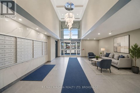 A spacious hallway with blue carpeting and a glass ceiling light fixture.