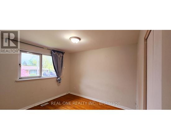 A room with a window and a wooden floor.
