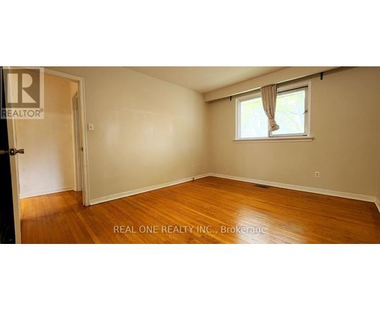 A room with wooden floors and a window with curtains.