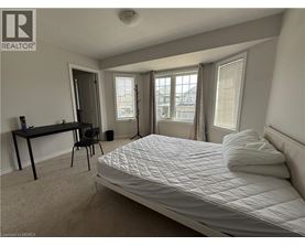 A bedroom with a large bed, a desk, and a chair.