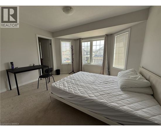 A bedroom with a large bed, a desk, and a chair.