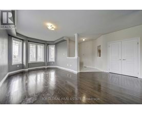 A spacious room with wood flooring and white walls.