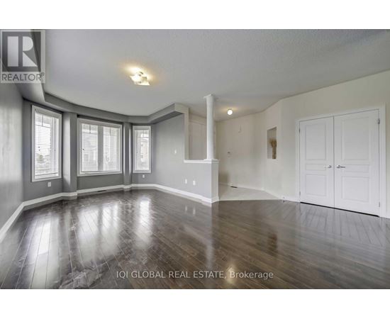 A spacious room with wood flooring and white walls.