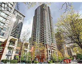 A tall building stands in front of a row of smaller buildings.