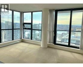 A large, empty room with a view of the cityscape outside the windows.