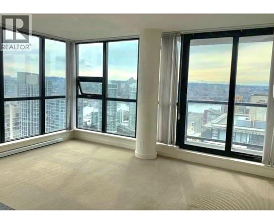 A large, empty room with a view of the cityscape outside the windows.