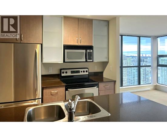 A kitchen with a stainless steel refrigerator, microwave, oven, and sink.