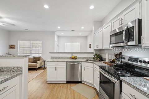A modern kitchen with white cabinets and stainless steel appliances.