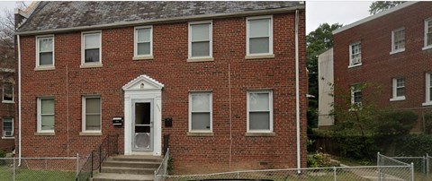 A red brick building with a white door and windows.