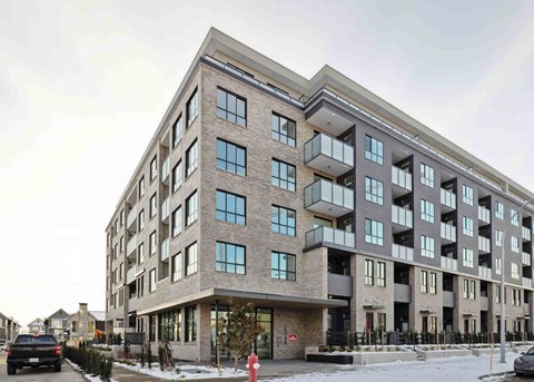 A large, modern building with a mix of brick and stone facade, featuring multiple balconies and large windows.