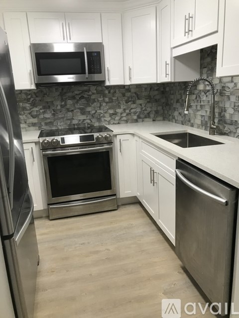 A kitchen with white cabinets and a stainless steel refrigerator.
