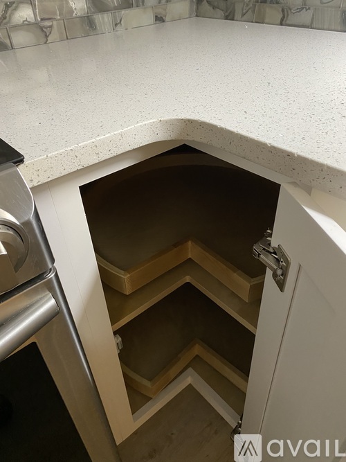 A kitchen with a white counter top and a cabinet with a pull out drawer.