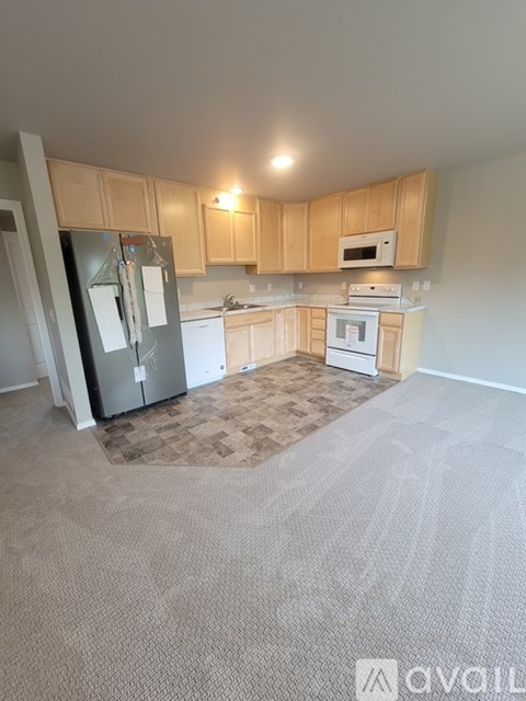 A kitchen with a refrigerator, microwave, oven, and sink.