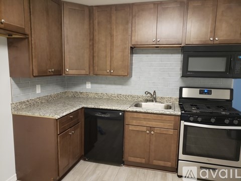 A kitchen with brown cabinets and a black dishwasher.