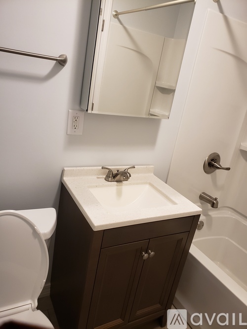 A white sink with a brown cabinet and a white toilet in a bathroom.