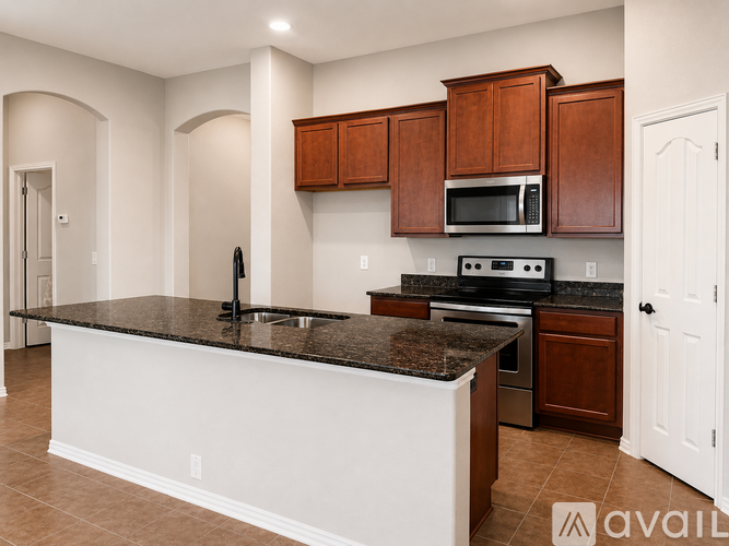 A kitchen with brown cabinets and a black countertop.