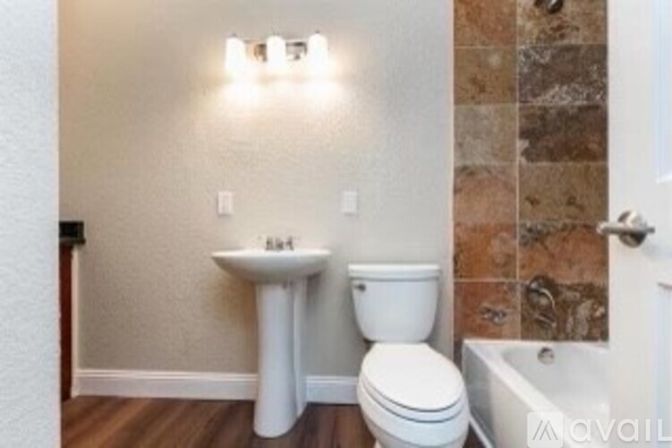 A bathroom with a toilet, sink, and tiled wall.