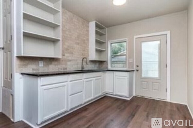 A kitchen with white cabinets and a wooden floor.
