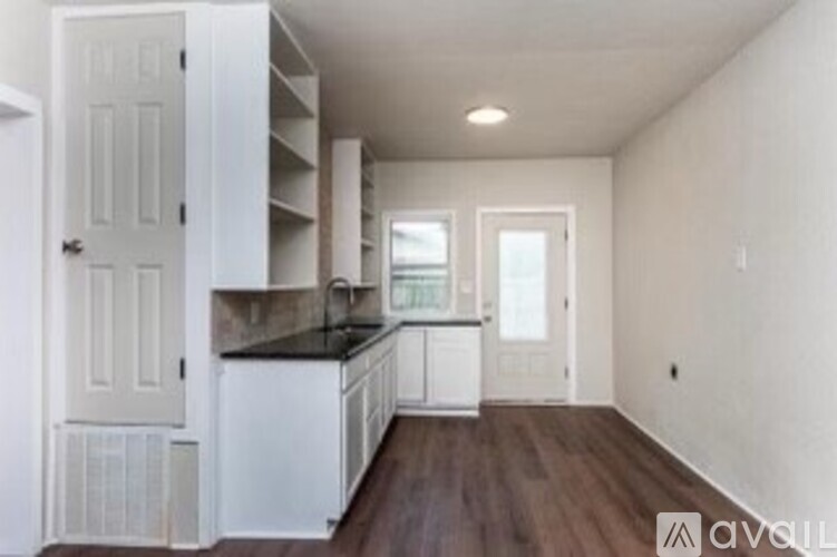A kitchen with white cabinets and a black countertop.