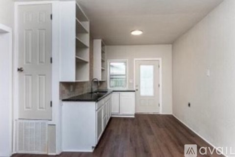 A kitchen with white cabinets and a black countertop.