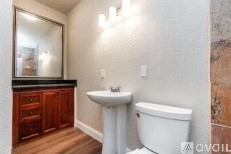 A bathroom with a white toilet, sink, and wooden cabinets.