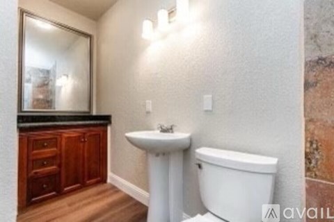 A bathroom with a white toilet, sink, and wooden cabinets.