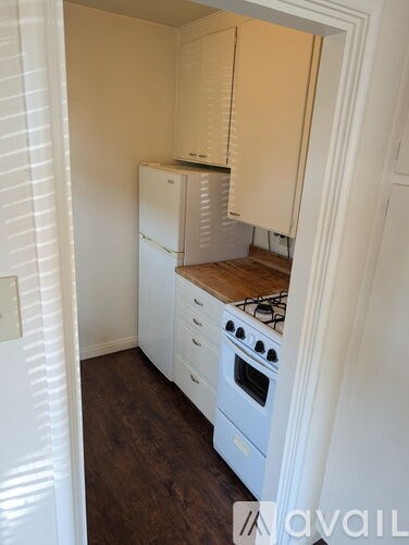 A kitchen with white appliances and wooden floors.