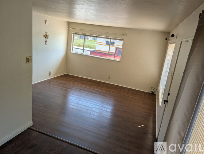 A room with wooden floors and a window showing a view of a street.