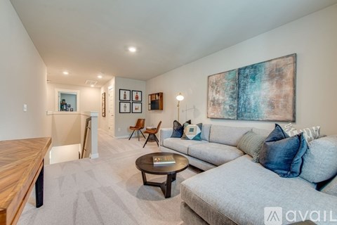A living room with a grey couch, a wooden table, and a painting on the wall.