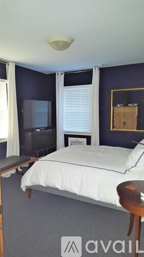 A bedroom with a bed, a chair, and a television.