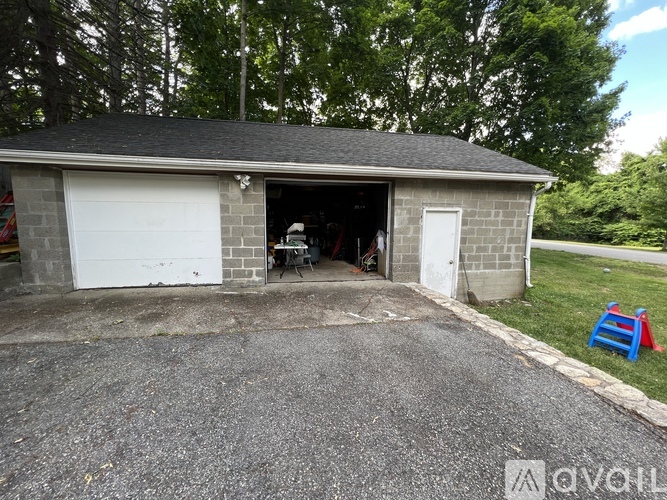 A garage with a white door is open and a blue stool is in front of it.