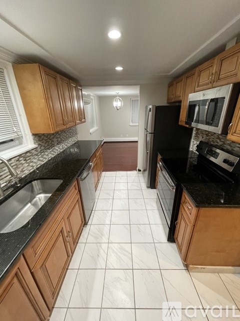 A kitchen with black countertops and white tiled floors.