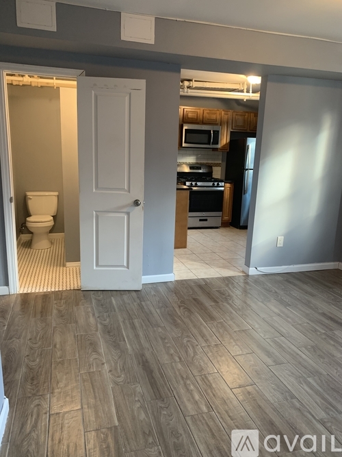 A room with a wooden floor and a white door leading to a bathroom.