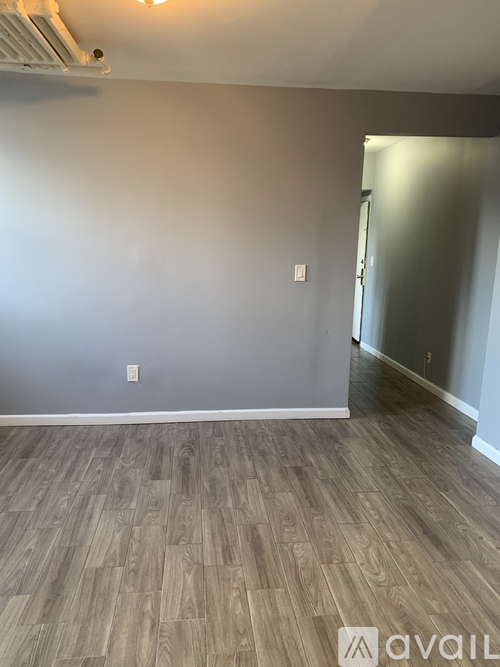 A room with a light grey wall and a wooden floor.
