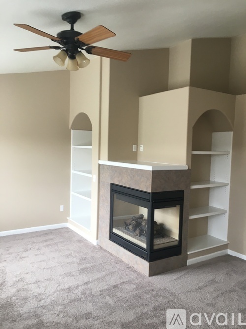 A living room with a fireplace and a ceiling fan.