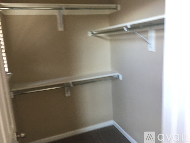 A small, empty room with a door on the left and a white shelf on the right.