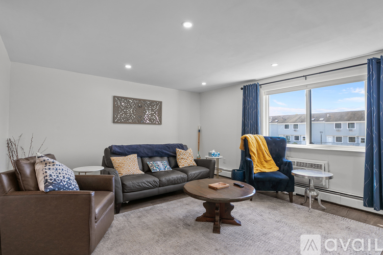 A living room with a brown leather couch, a brown leather armchair, a brown coffee table, and a blue chair with a yellow throw.