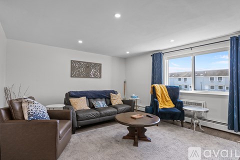A living room with a brown leather couch, a brown leather armchair, a brown coffee table, and a blue chair with a yellow throw.