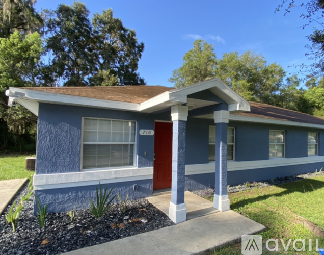 A blue house with a red door and a brown roof.