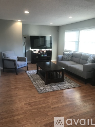A living room with a grey couch, a grey armchair, a black coffee table, and a flat screen TV.