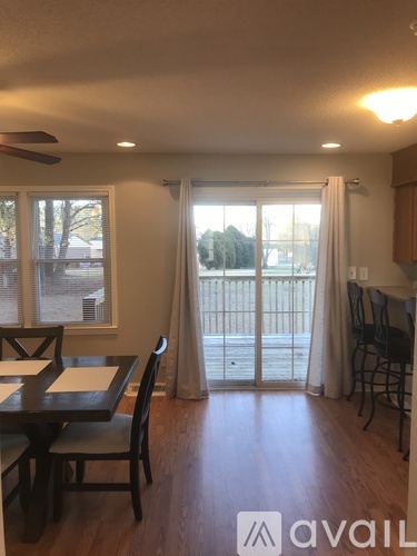A dining room with a table and chairs and a sliding glass door.