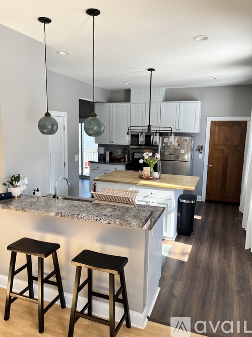 A kitchen with a marble countertop and bar stools.