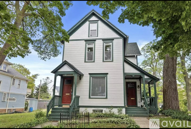 A two-story house with a red door and green stairs.