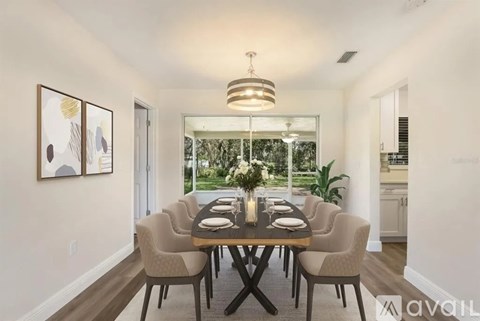 A dining room with a table set for four and a view of the backyard.