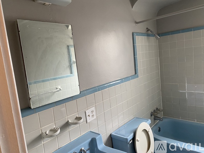 A bathroom with a blue tub and a mirror above it.