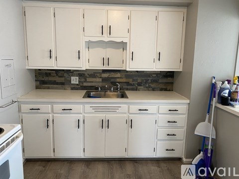 A kitchen with white cabinets and a stone backsplash.