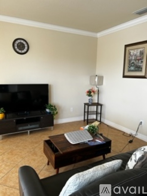 A living room with a black couch and a flat screen TV.