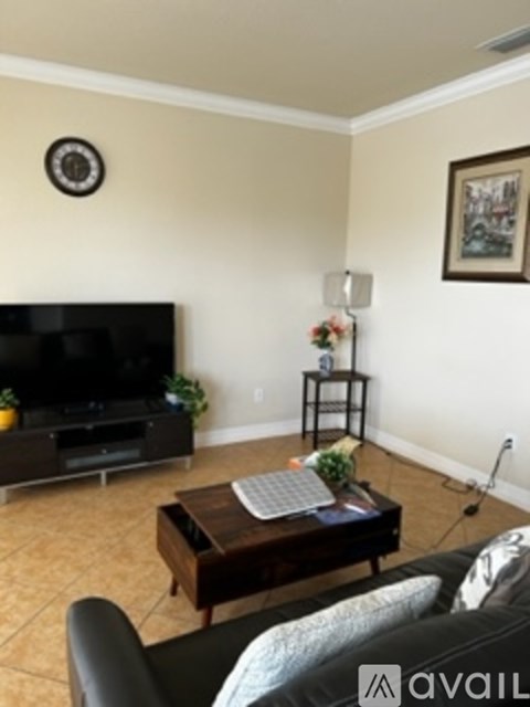 A living room with a black couch and a flat screen TV.