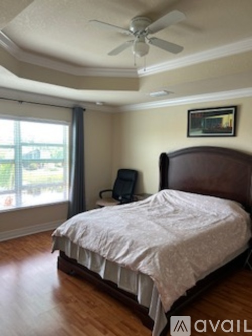 A bedroom with a bed, a fan, and a window.
