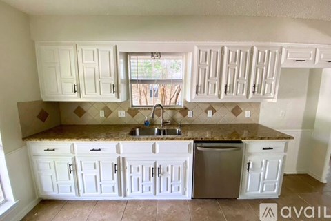 A kitchen with white cabinets and a granite countertop.